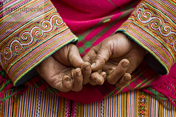 Hmong-Mädchen mit traditioneller bestickter Kleidung kreuzt die Finger