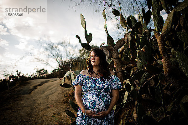 Schwangere Frau Mitte Dreissiger Jahre posiert im Kaktusgarten