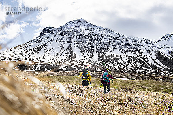 Zwei Skitourengeher wandern in Island in den Schnee.