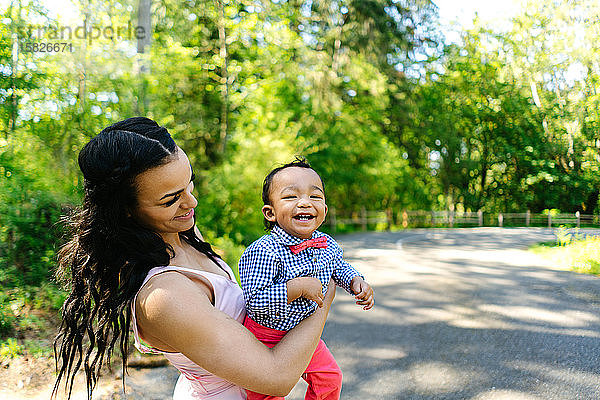 Eine Mutter hält ihren kleinen Sohn an einem Sommertag in einem Park