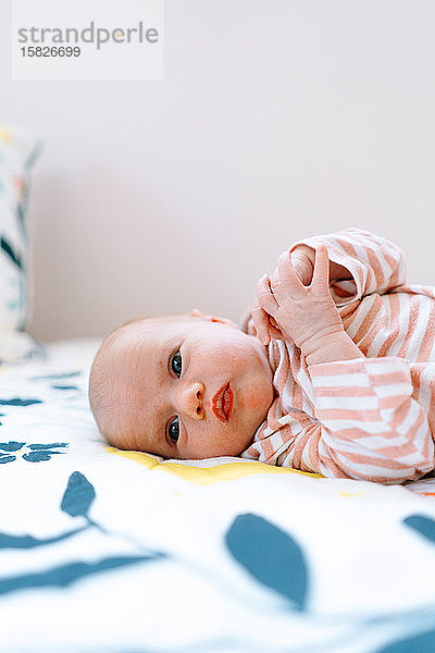 Nahaufnahme-Porträt eines neugeborenen Mädchens  das auf einer bunten Decke liegt