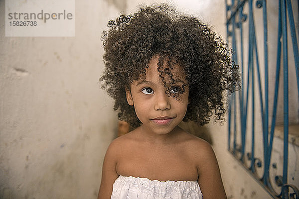 Schönes afro-brasilianisches Mädchen mit lockigem Haar und weißem Kleid  lächelt