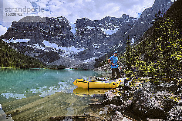 Ein Mann versammelt sich  um sich auf eine Rafting-Tour über den Cirque Lake in Banff vorzubereiten