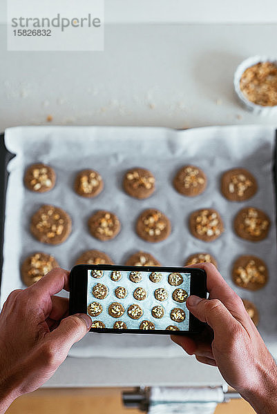 Draufsicht eines jungen Mannes  der seine selbstgebackenen Kekse fotografiert
