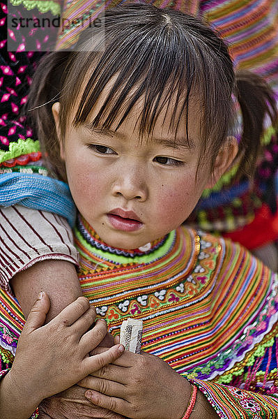 Junges Mädchen in traditioneller Kleidung  das die Hand seiner Mutter hält