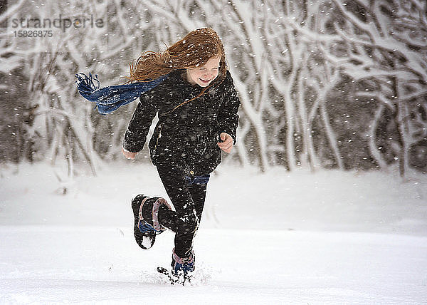 Junges rothaariges Mädchen spielt draussen im Schnee