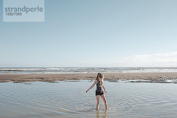 Mädchen geht am Strand durchs Wasser