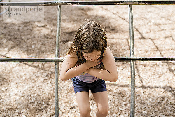 Junges Mädchen mit braunen Haaren spielt im Sommer an einem sonnigen Tag auf dem Spielplatz