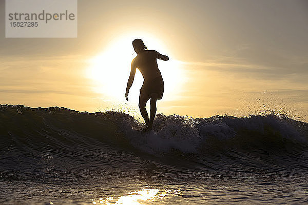Silhouette eines Surfers bei Sonnenuntergang