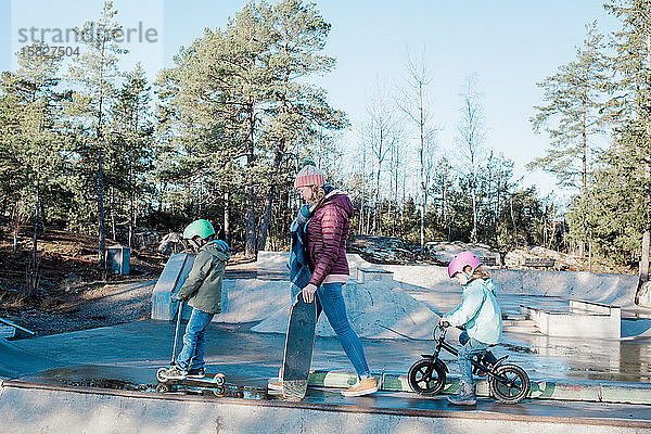 Mama und ihre Kinder laufen über einen Skatepark  um zu fahren und Spaß zu haben