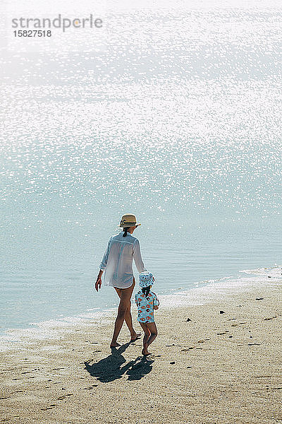 Mutter und Tochter gehen am Strand spazieren