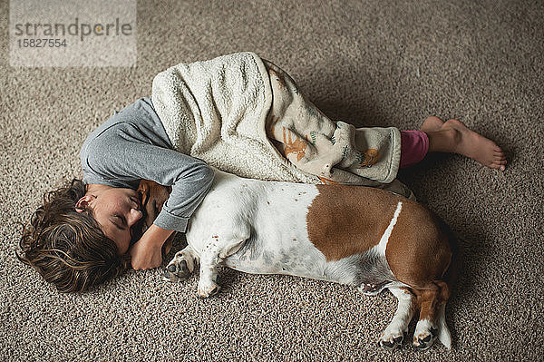 Junges Mädchen mit Dachshund in Decke auf dem Boden liegend