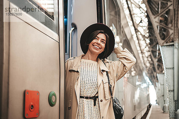 Junge stilvolle Reisende hängt und lächelt im Zug