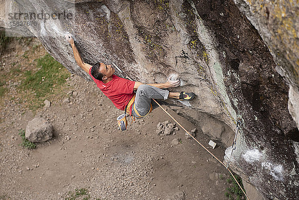 Ein Mann in Rot hält sich beim Felsklettern in Jilotepec