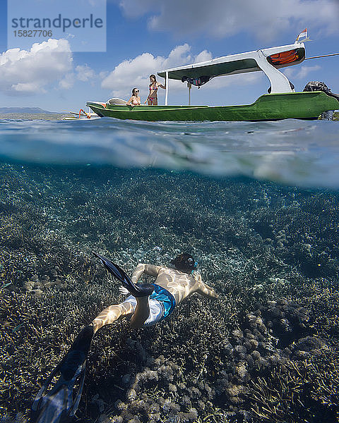 Junger Mann schnorchelt in der Nähe des Bootes im Meer  Unterwassersicht