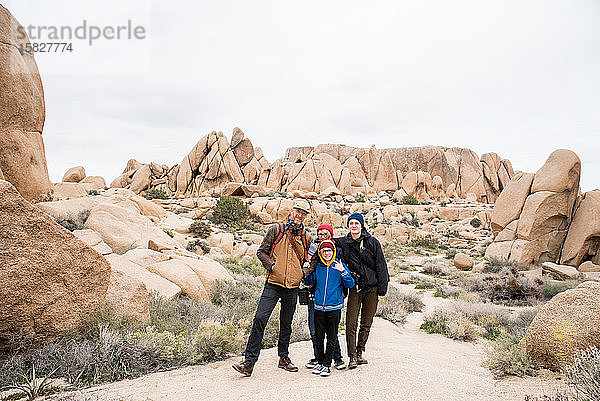 Vierköpfige Familie vergnügt sich umgeben von Felsen und Sträuchern in der Wüste