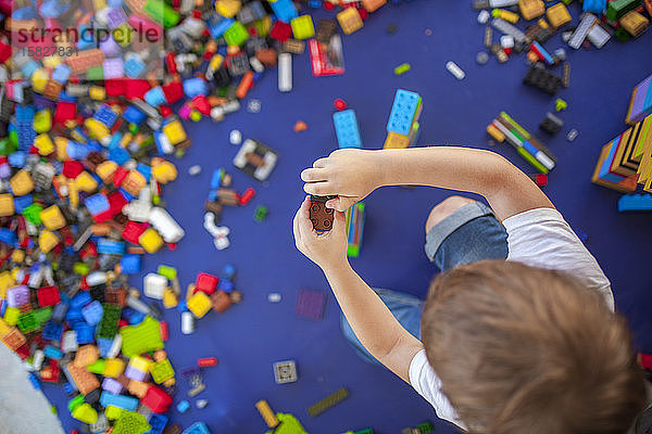 4 Jahre Junge baut einen Turm mit ineinandergreifenden Kunststoffziegeln