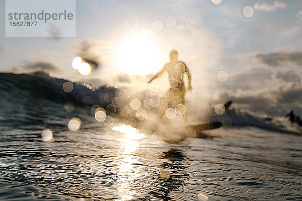 Surfer auf einer Welle zur Zeit des Sonnenuntergangs