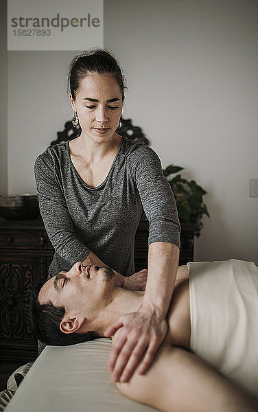 weibliche Massagetherapeutin behandelt männlichen hispanischen Patienten