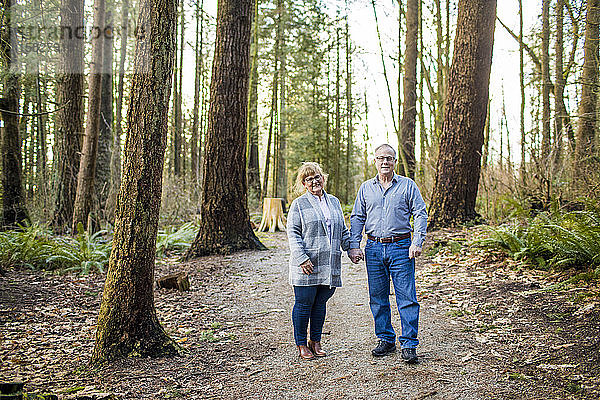 Älteres Paar  das im Wald Händchen hält.