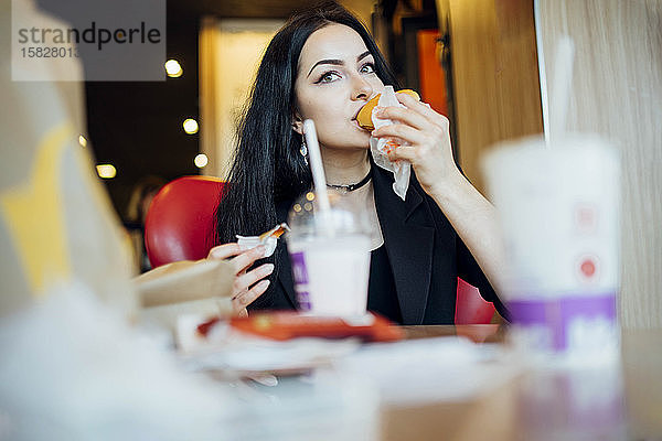 Frau isst einen Hamburger in einem Cafe