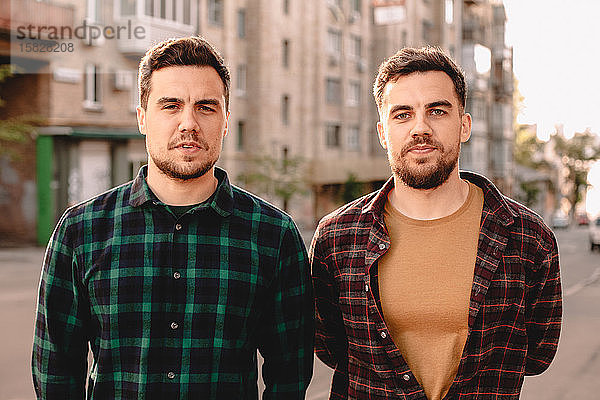 Porträt von erwachsenen Zwillingsbrüdern  die im Sommer auf der Straße der Stadt stehen