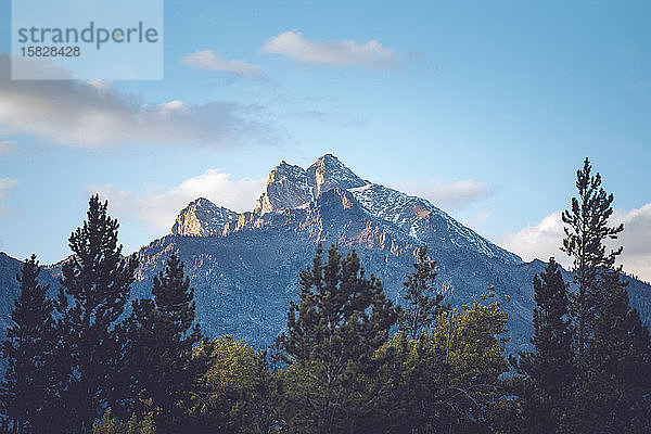 Ein Berggipfel wird von goldenen Strahlen der untergehenden Sonne beleuchtet.