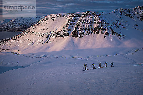 Personengruppe beim Skilanglauf bei Sonnenaufgang in Island