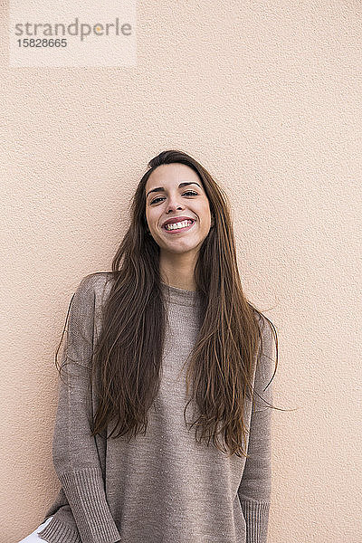 Porträt einer lächelnden Frau  die an einer Wand in Boadilla del Monte lehnt