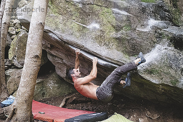 Ein männlicher Felskletterer klettert im Freien auf einen Felsen