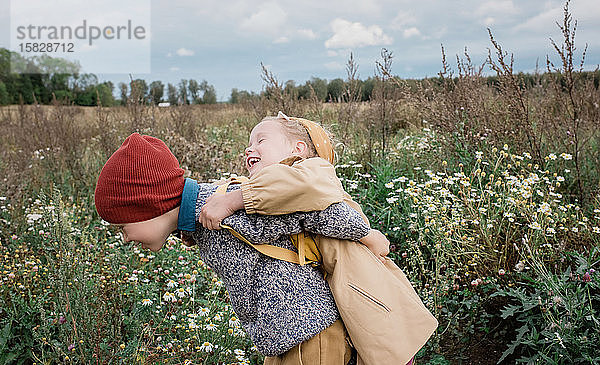 Umarmen und Lachen der Geschwister beim Spielen im Freien
