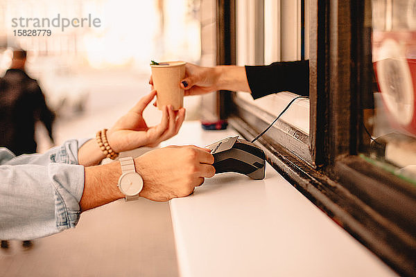 Kunde bezahlt mit Kreditkarte und kauft Kaffee auf der Straße in der Stadt