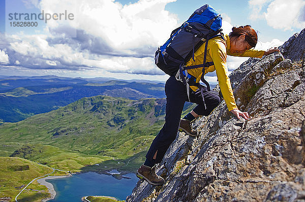 Frau klettert mit Rucksack auf den Snowdonia-Berg