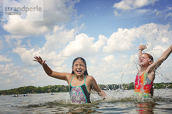 Zwei junge Mädchen im Badeanzug planschen in einem See