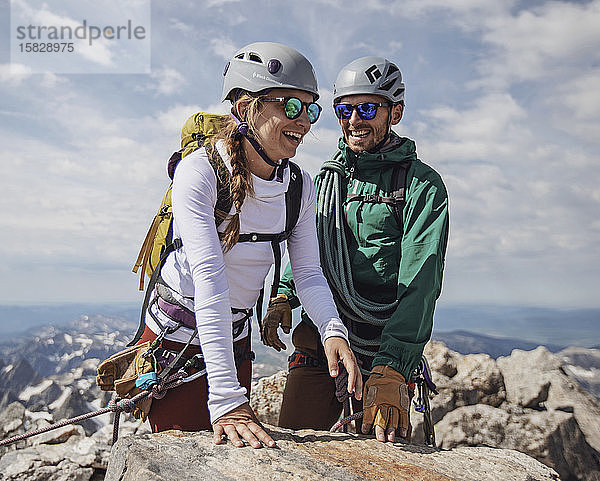 Ein Paar lächelt vor Freude  nachdem es den Gipfel des Grand Teton in Wyoming erreicht hat