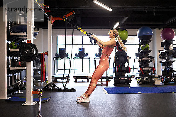 Eine athletische Frau  die sich im Fitnessstudio in die Zeit legt.