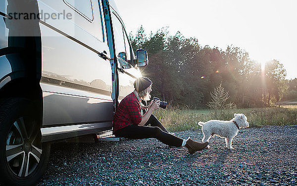 Frau  die beim Camping im Sommer ein Bild ihres Hundes spricht