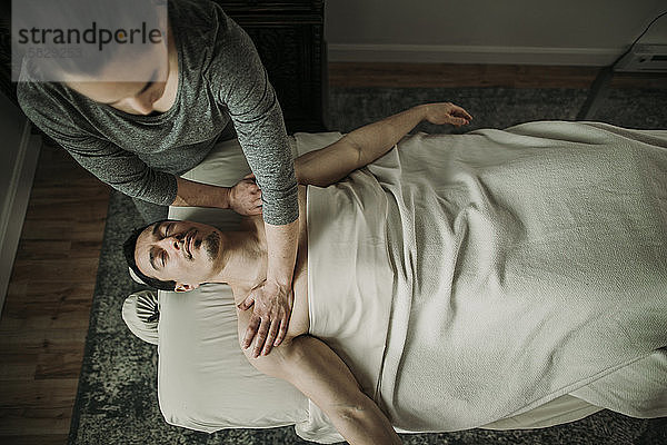 Weibliche Massagetherapeutin übt Druck auf die Schultern des Mannes aus