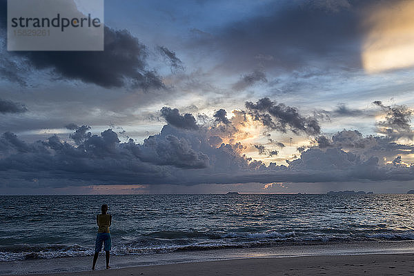Eine Reisende beobachtet den Sonnenuntergang an einem Strand der Insel Koh Lanta  Thailand.