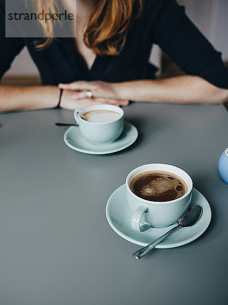 Eine Frau und zwei Tassen Kaffee im Café