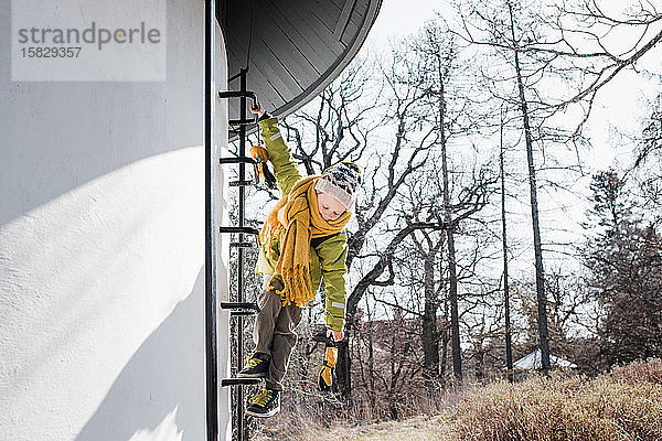 Junge klettert im Winter auf einen Wasserturm