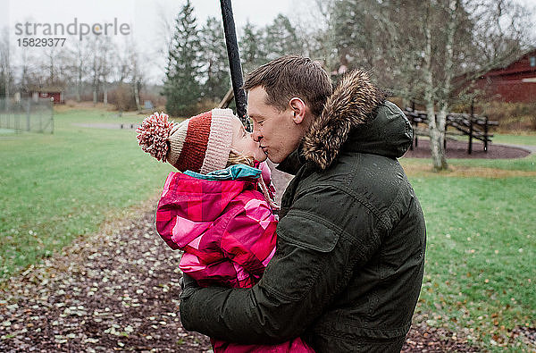 Vater  der seine Tochter küsst  während er draußen in einem Park spielt