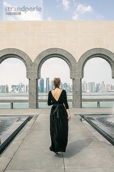 Rückansicht einer jungen Frau  die in Doha geht und auf das Meer schaut