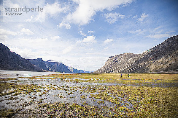 Zwei Rucksacktouristen durchqueren die nasse Tundra am Akshayak-Pass.