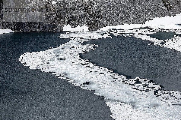 Das letzte bisschen Eis schmilzt im Sommer von einem Alpensee.