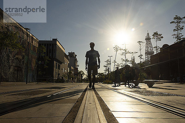 Silhouette eines Mannes  der über Straßenbahnschienen in der Innenstadt läuft