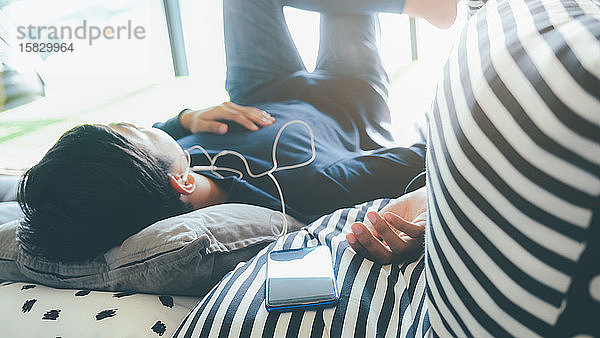 Junger Mann entspannt sich beim Hören der Musik vom Mobiltelefon aus.