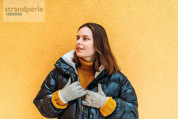 Junge Frau an gelber Wand stehend