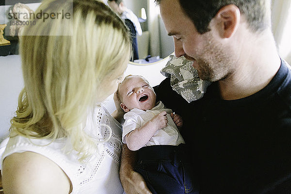 Ein neugeborener Junge lächelt  während ihm seine Eltern helfen