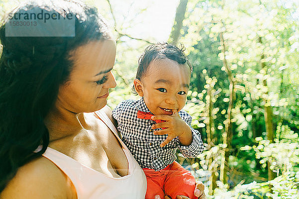 Nahaufnahme eines lächelnden kleinen Jungen  der von seiner Mutter gehalten wird